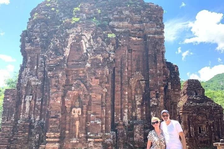 Group photo of travellers in the My Son Sanctuary valley with red-brick Cham ruins in the background.