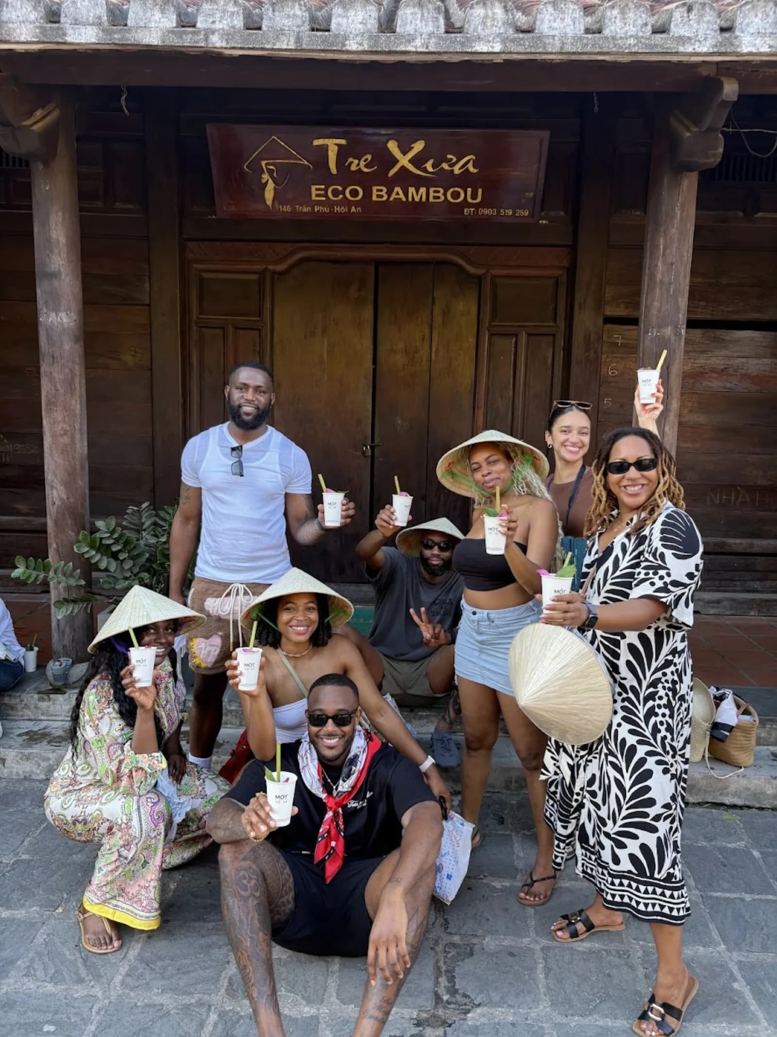 Guests toasting with cups of Mot herbal tea in front of the Tre Xua cafe on Tran Phu street.