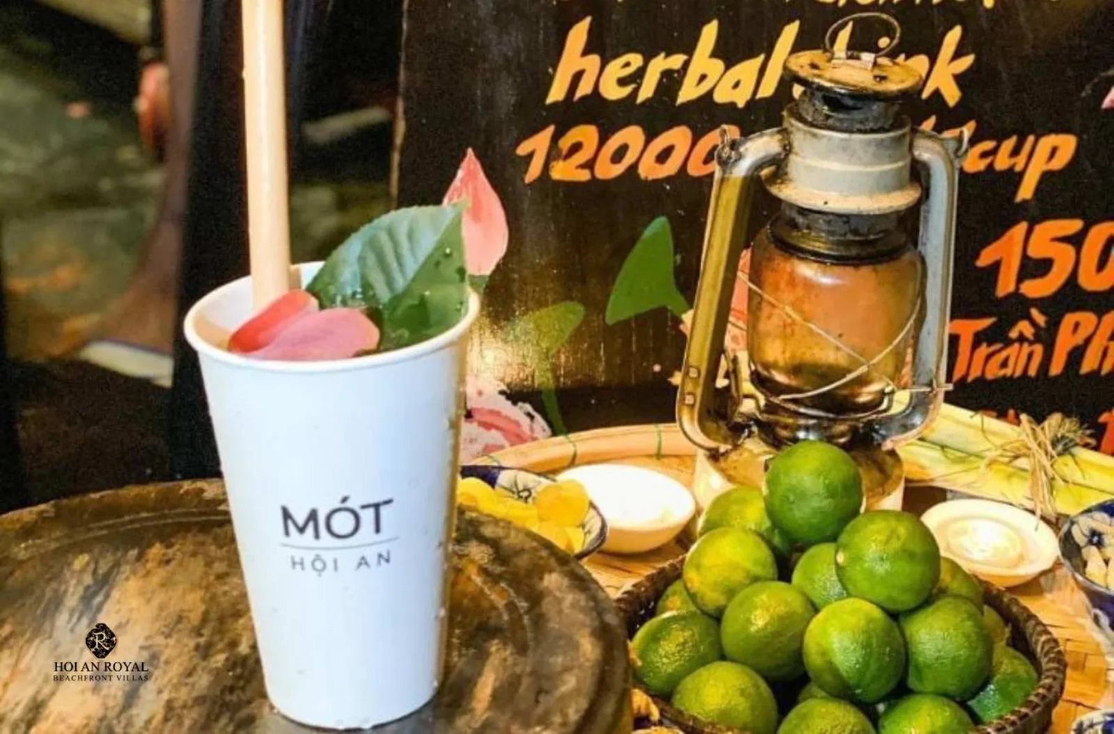 A cup of Mot herbal tea with a lotus petal, limes and cinnamon on the stall counter.