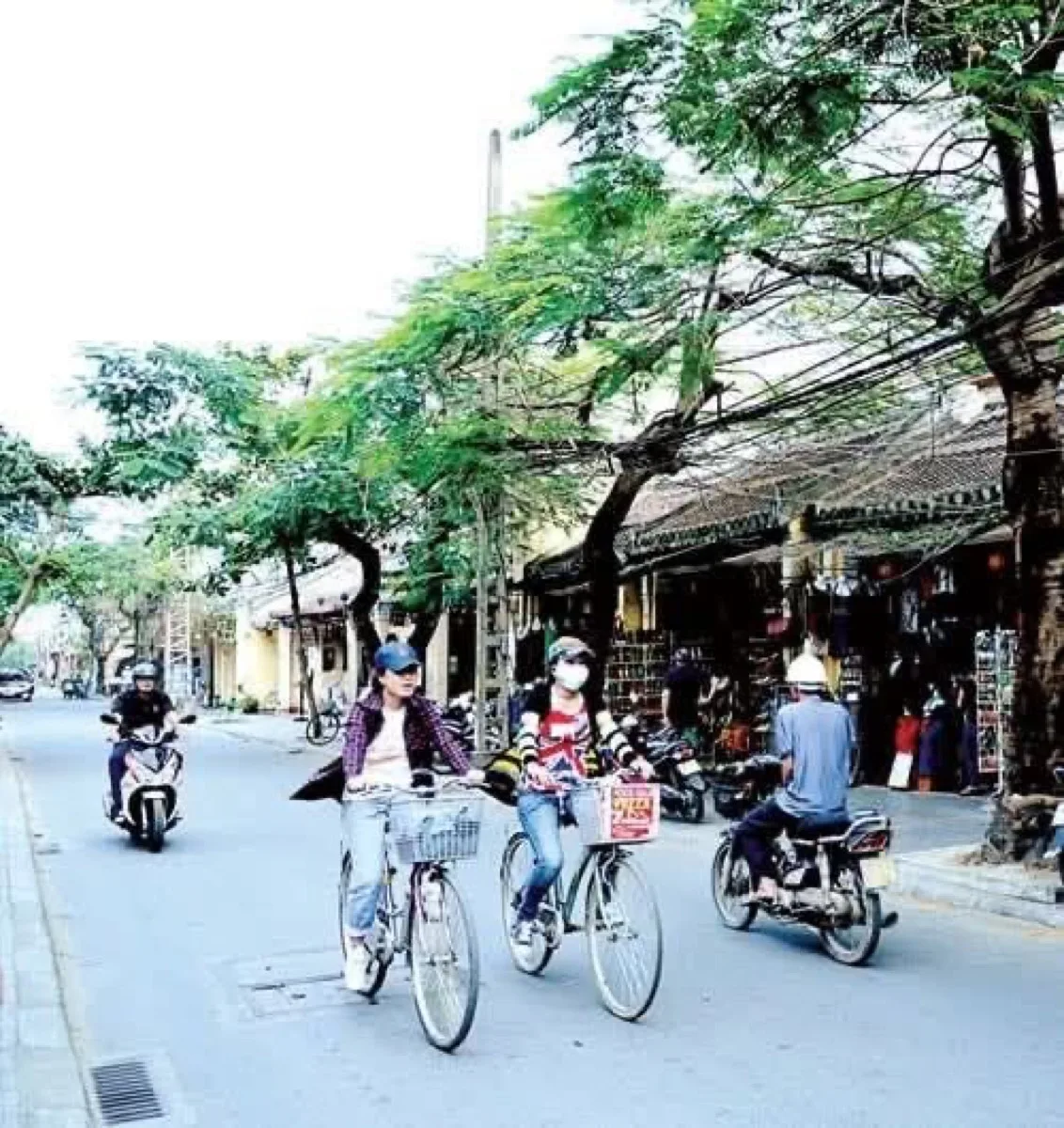Small bowls of che (Vietnamese sweet soup) with black beans and coconut milk at a street stall in Hoi An, plastic stools and a busy alley in the background