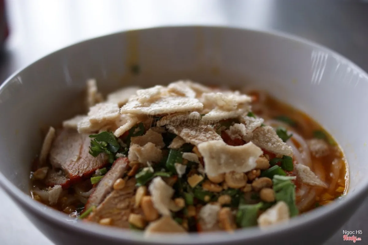 Mì Quảng served with fresh herbs, peanuts, and rice crackers