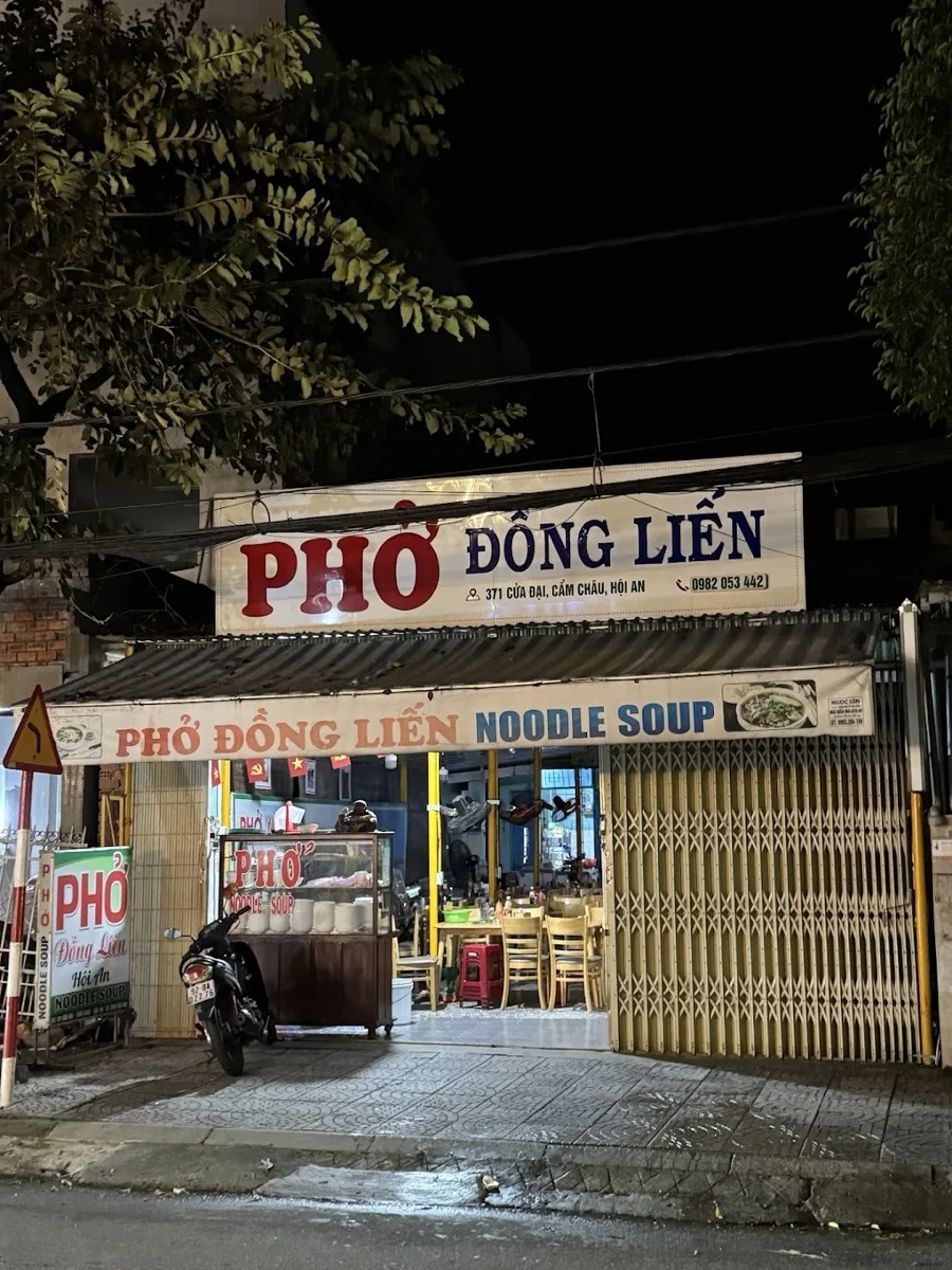 Phở Đồng Liến at night — the lit sign over 371 Cửa Đại, noodle cart parked out front