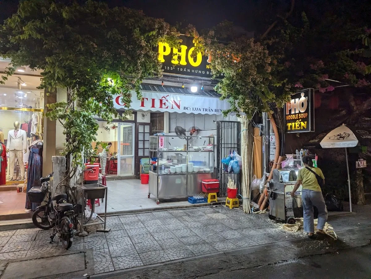 Phở Tiến at 133 Trần Hưng Đạo at night, noodle cart and glass cabinet ready for service