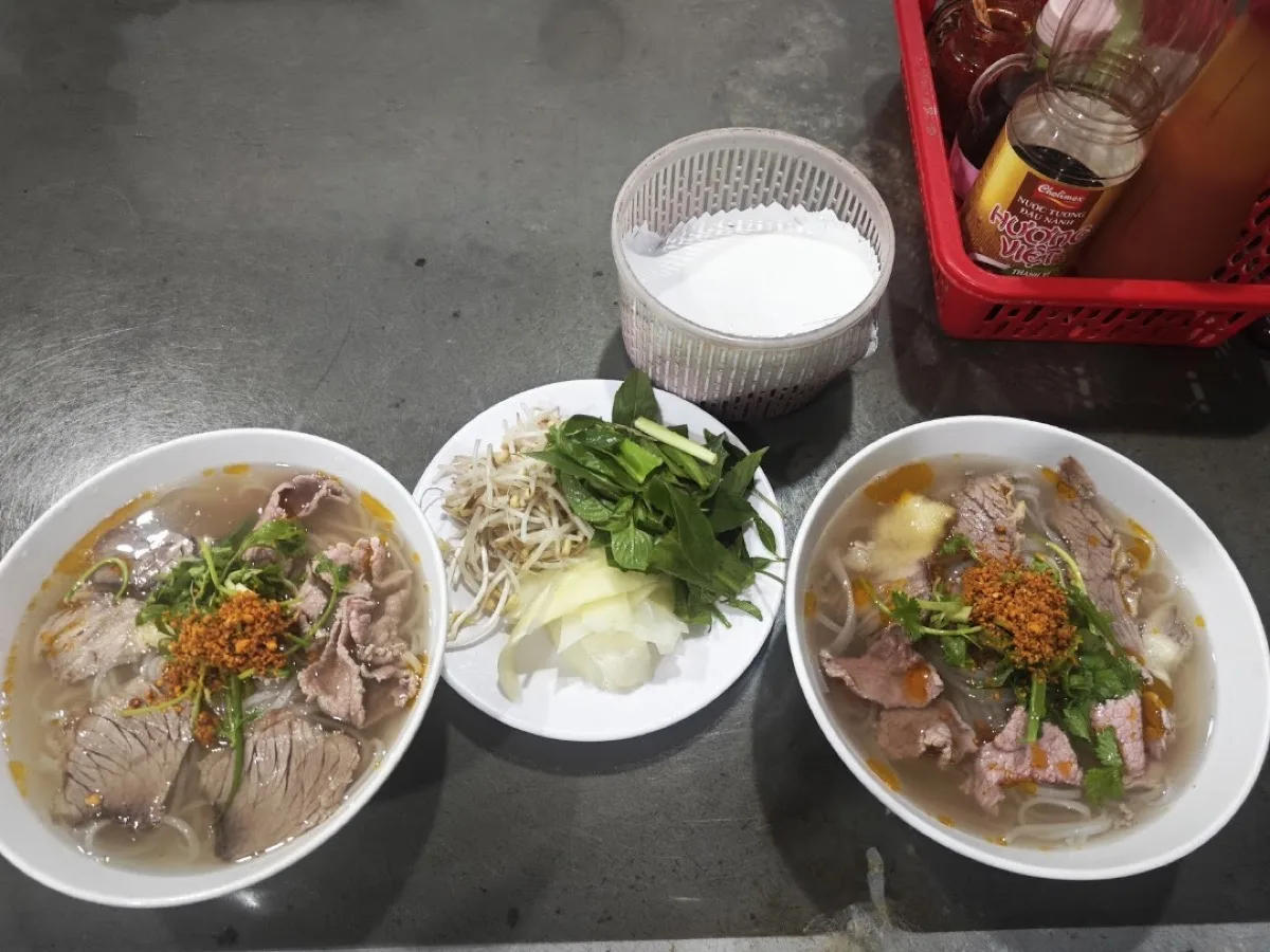 Two bowls of beef pho for two at Phở Tuấn, condiment basket between them