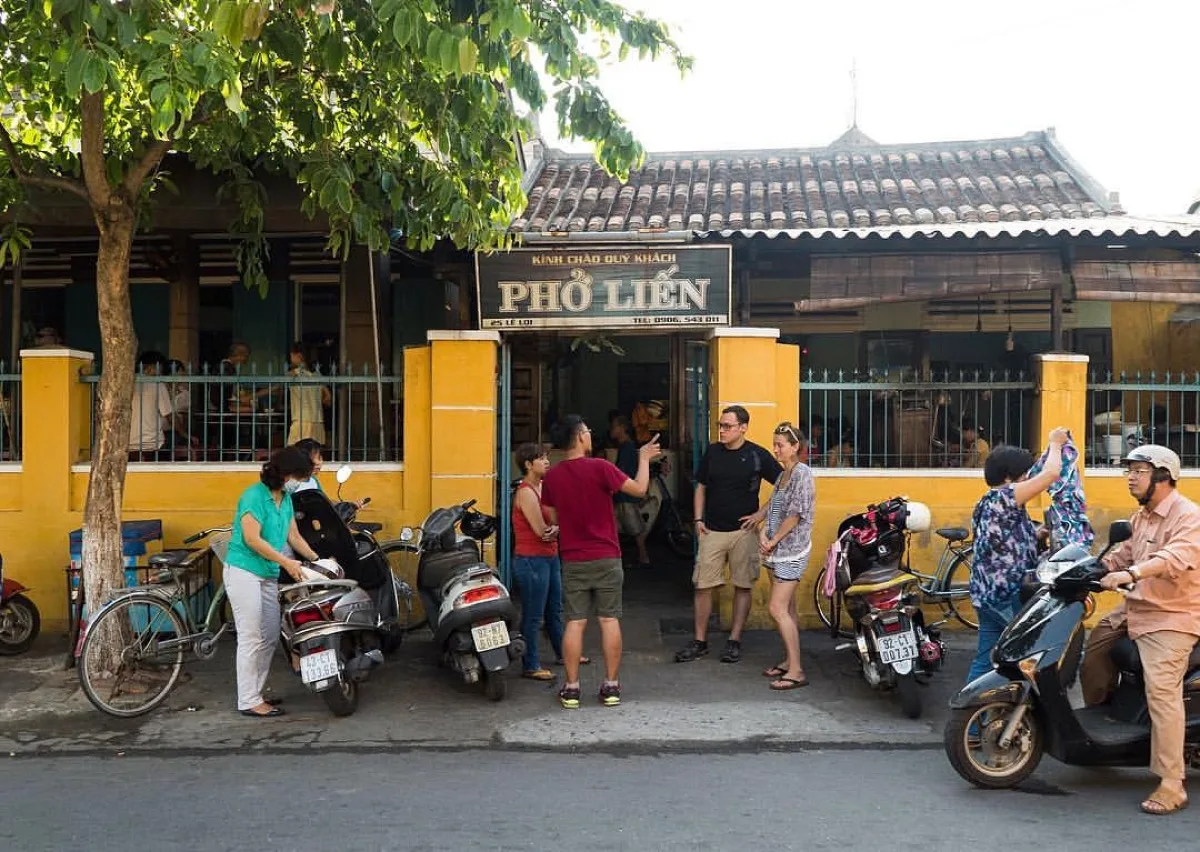 The original Phở Liến storefront at 25 Lê Lợi photographed in 2017 — sign with the old Quảng Nam phone code, customers on the sidewalk