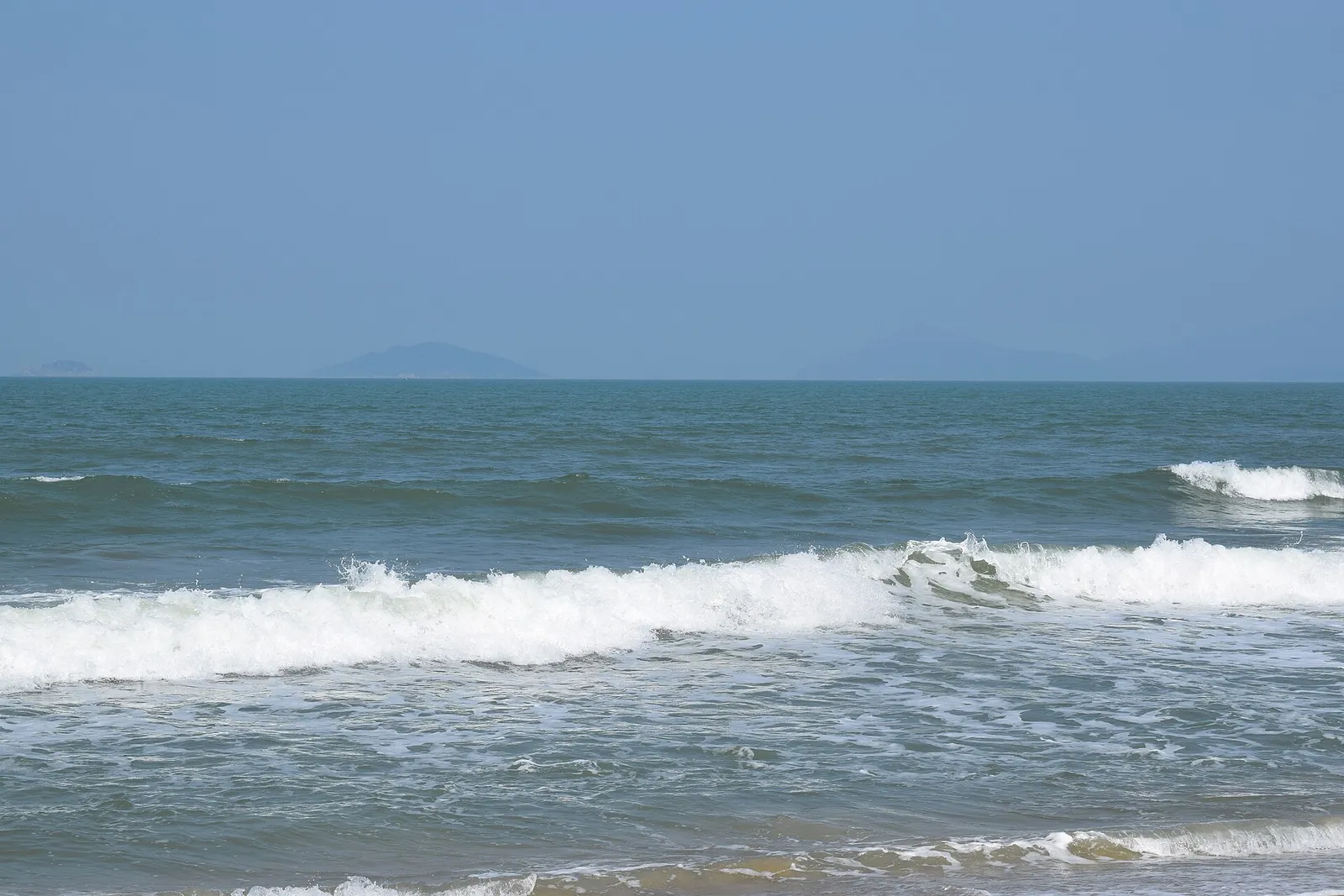 Breaking waves at An Bang beach with the Cham Islands on the horizon.