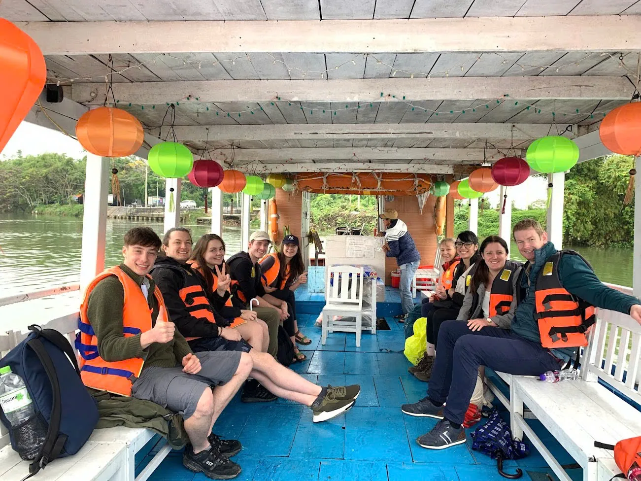 Guests in life jackets on a covered river boat at the end of a Hoi An day trip.