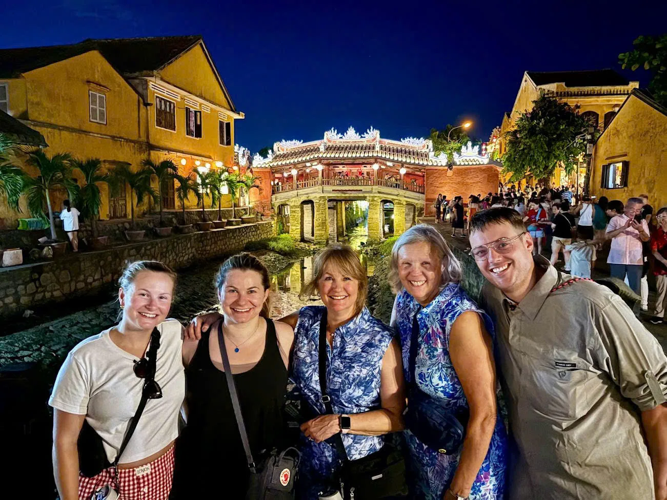 A private group in front of the illuminated Japanese Covered Bridge in Hoi An at night.