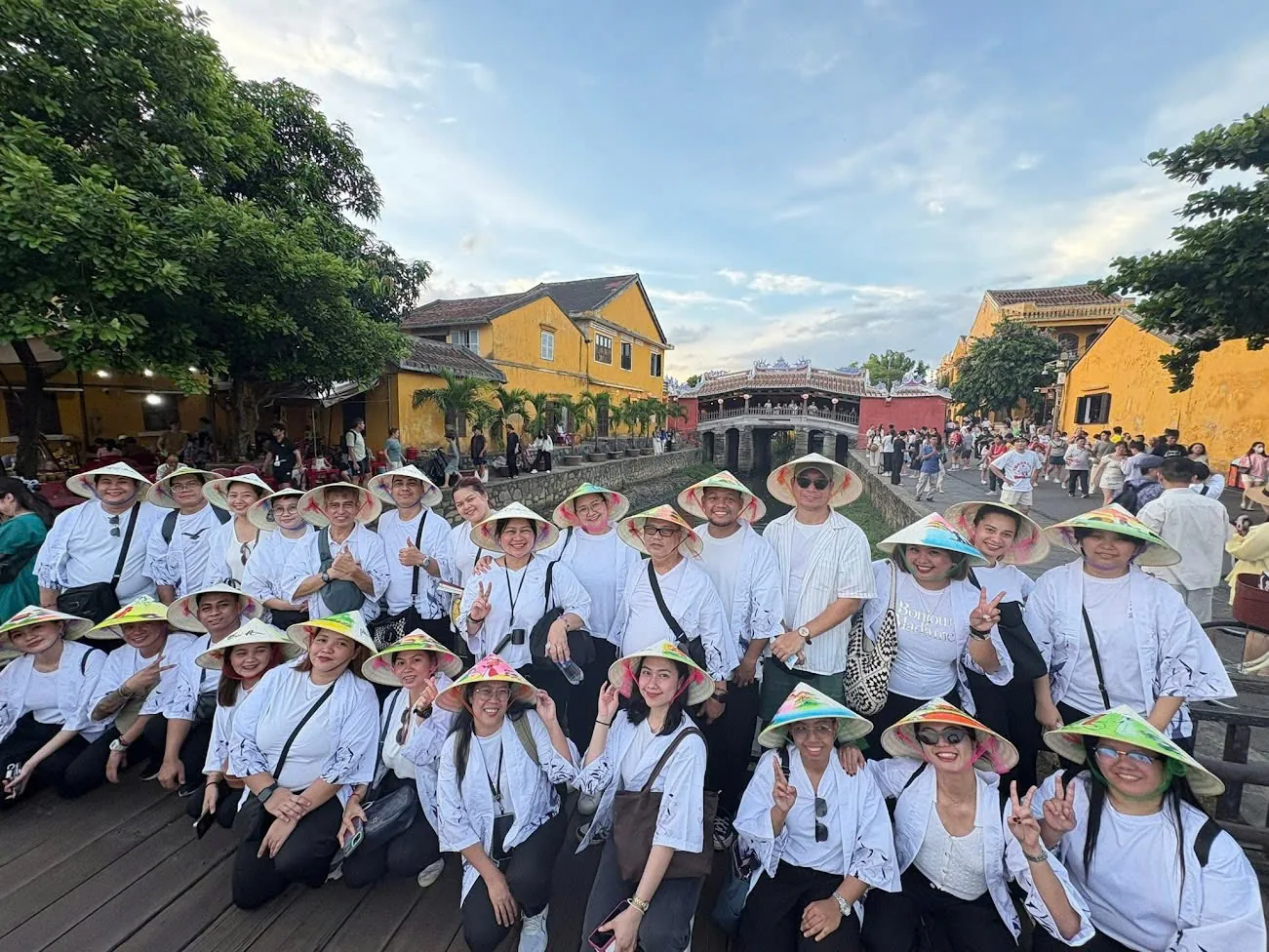 Guests in conical hats at the Hoi An riverside at the end of a transfer with stops.