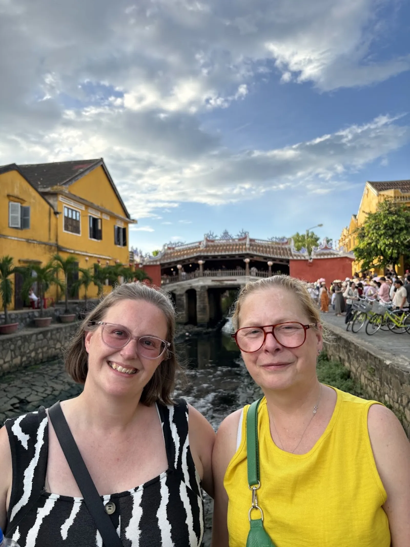 Two travellers taking a selfie with the Japanese Covered Bridge behind them.