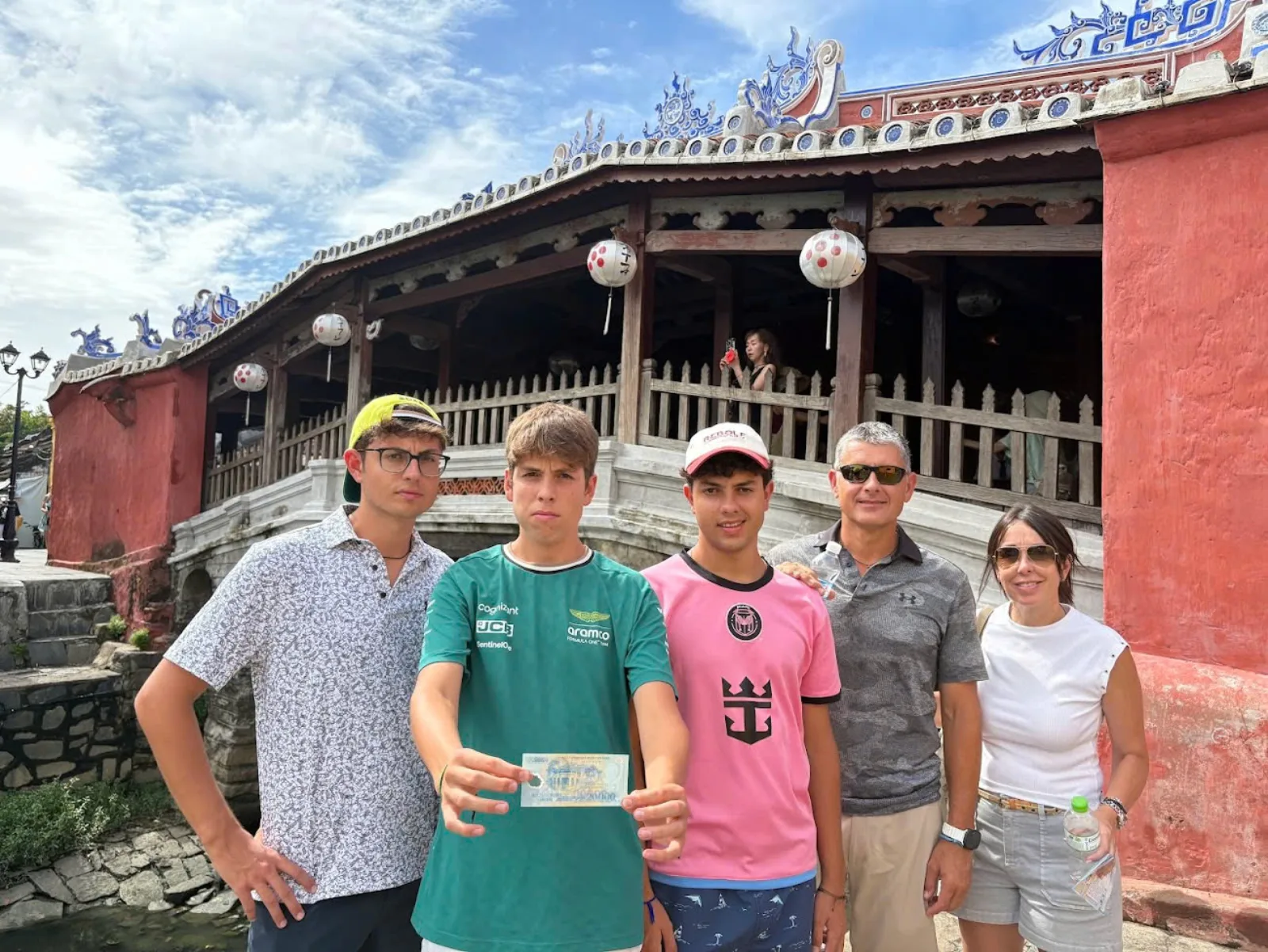 Five guests photographed at the red gate of the Japanese Covered Bridge in Hoi An Old Town.