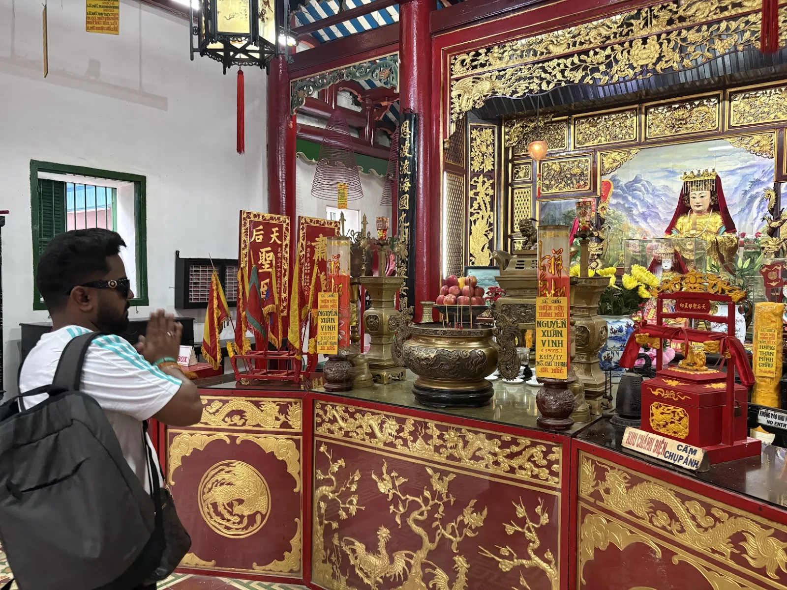 A guest pausing at a worship altar while Fin shares the story of the Mother Goddess tradition in Hoi An.