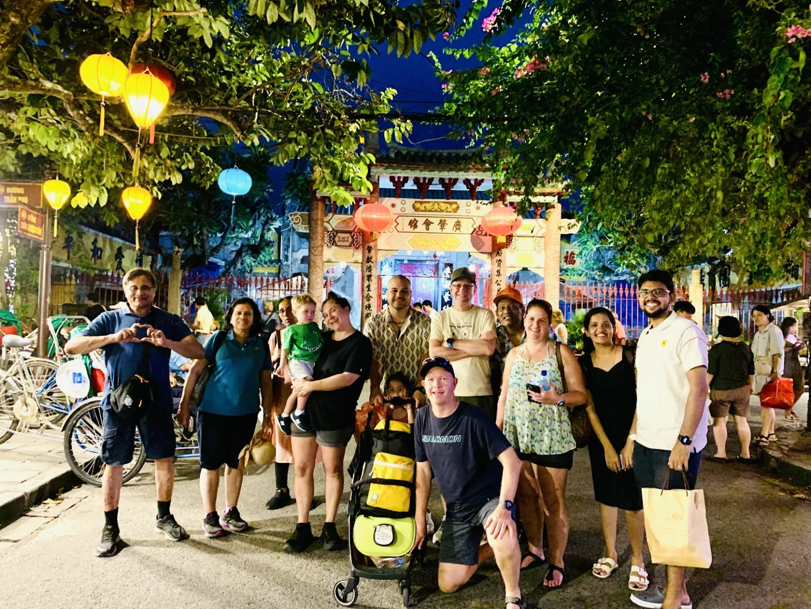 A private tour group in front of Hainan Assembly Hall at night with lanterns glowing above.