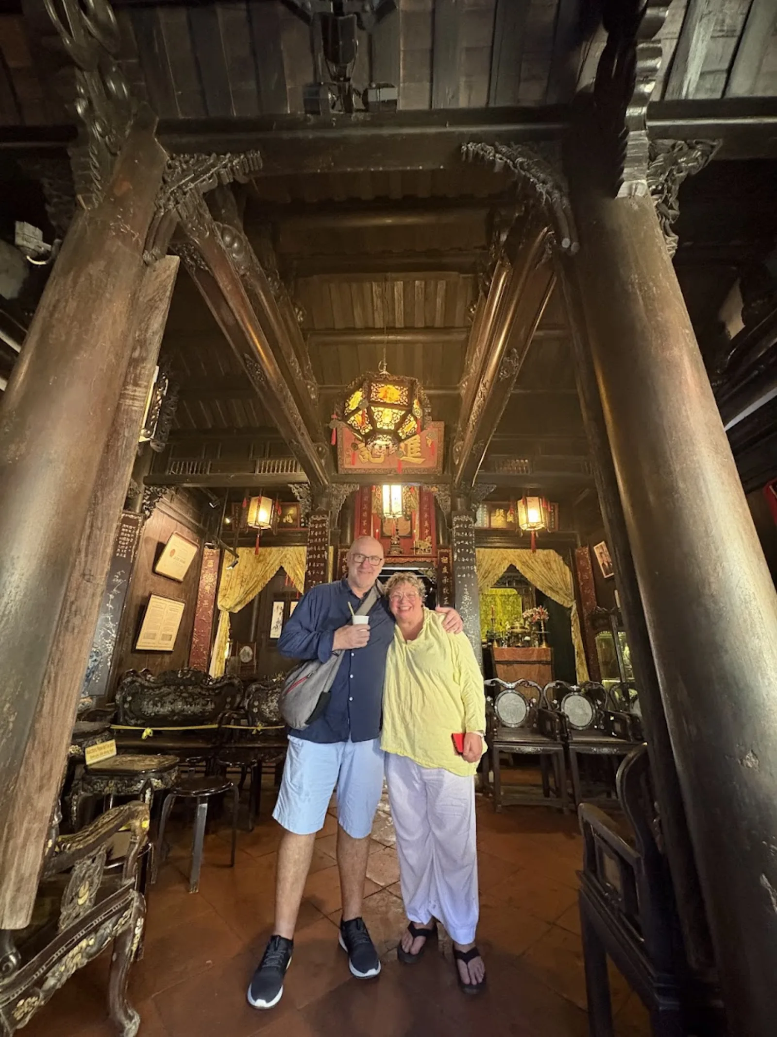 A guest inside a Hoi An ancient house, under its dark timber frame and shuttered front.