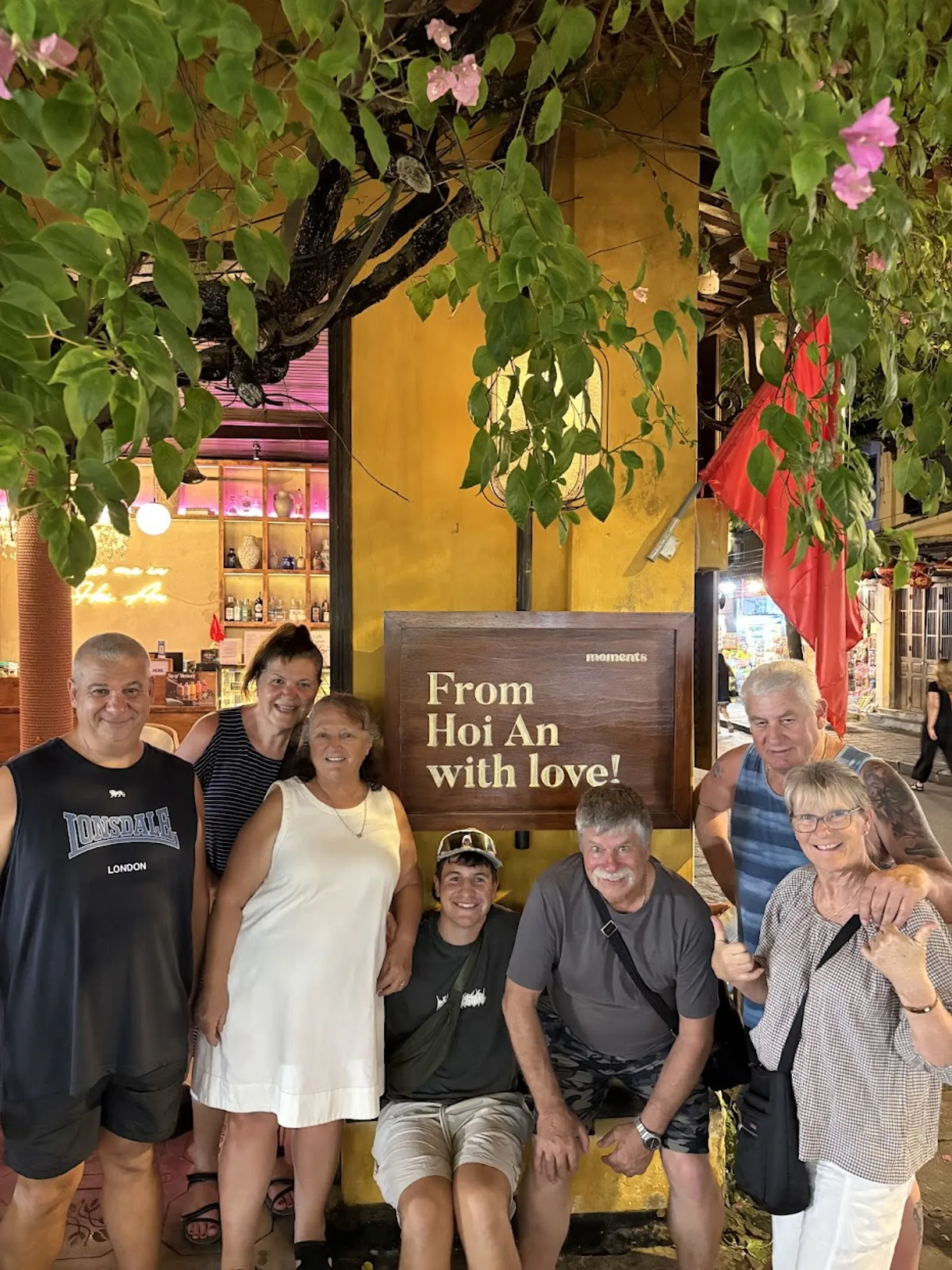 A group of seven guests beside the 'From Hoi An with love' wall in the Ancient Town.