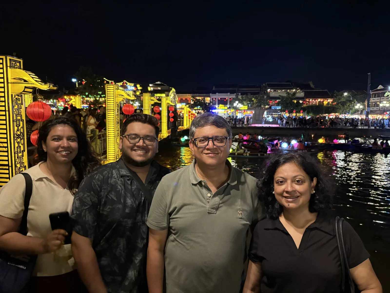 Four guests photographed by the Hoai River at night surrounded by red lantern light.