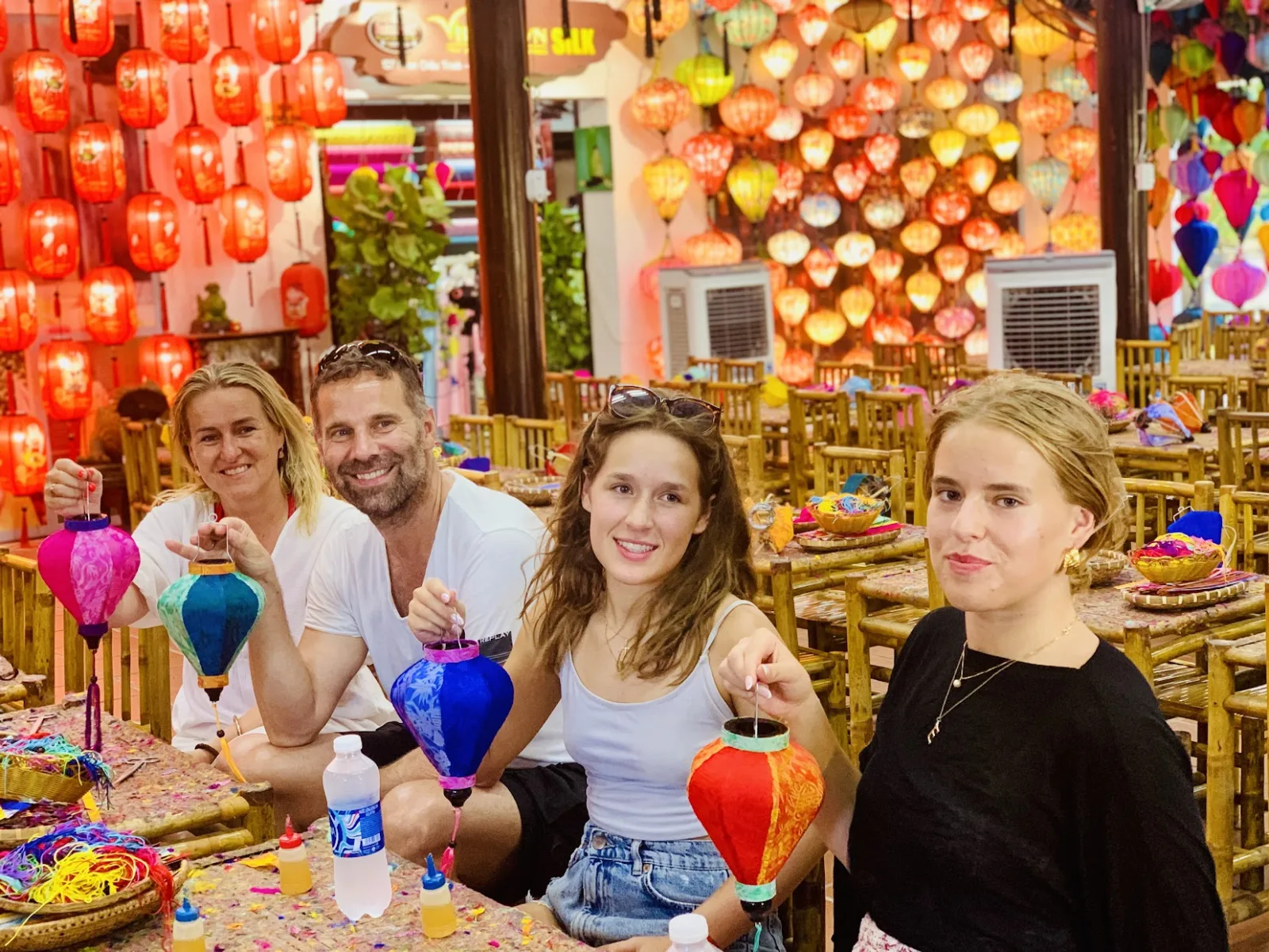 Four guests showing off the mini silk lanterns they decorated during a Hoi An workshop.